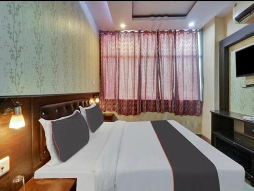 a bedroom with a large white bed in front of a window at CORAL TREE INN in Lucknow