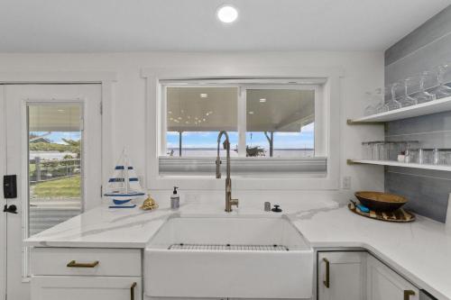 a white kitchen with a sink and a window at New DRIFTWOOD SHORES ROAD HOUSE CAMANO in Driftwood Shores