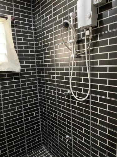 a shower in a bathroom with black tiles at Two Bedroom Holiday Home- Olosara Sigatoka Guest House in Singatoka