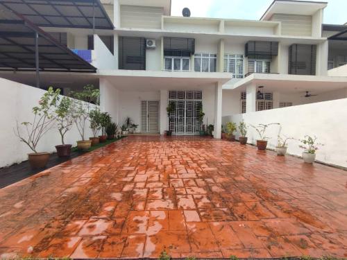 a large white house with a red brick courtyard at Dhana Palace Homestay Gelang Patah in Johor Bahru