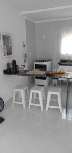 a kitchen with a counter and stools in a room at Casa de Campo em Lumiar com corrego ,lareira e churrasqueira in Lumiar