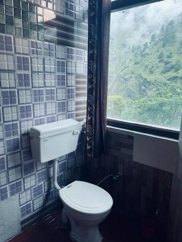 a bathroom with a toilet and a window at Hotel Virdh Badri in Joshīmath