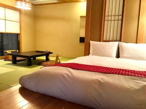a bedroom with a large bed and a table at Toushinan Komeya in Ito