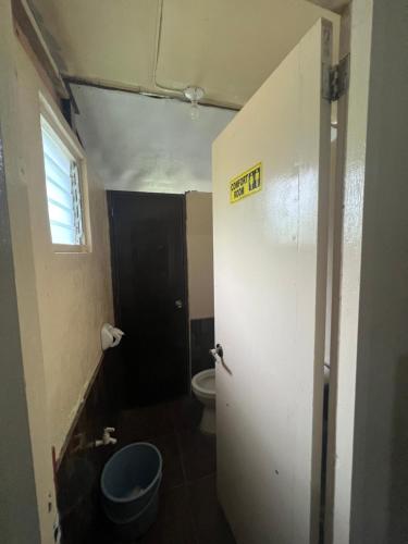 a bathroom with a toilet and a door with a sign on it at Gratum Beach Resort in Dapitan