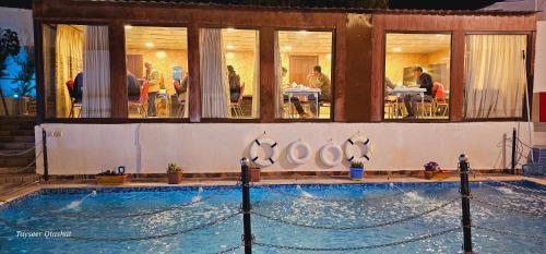 a swimming pool in front of a building with people eating at Al Namteh Lodge in ‘Ābil