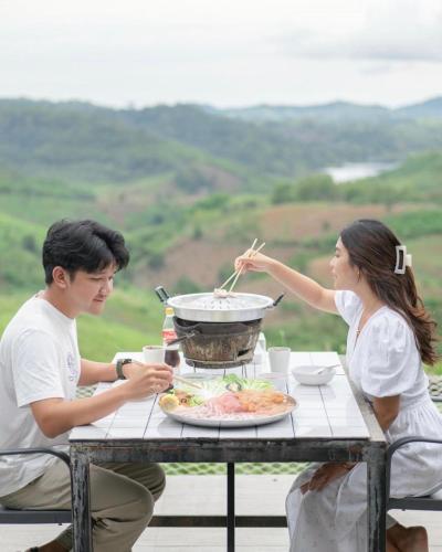 a man and a woman sitting at a table with a meal at Papa Garden Khaokho in Khao Kho