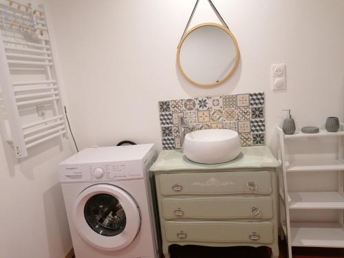 ein Badezimmer mit einer Waschmaschine und einem Spiegel in der Unterkunft chez Marie et Lulu 