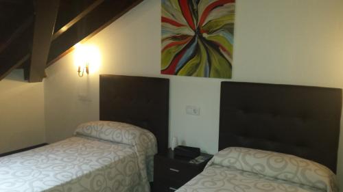 a bedroom with two beds and a painting on the wall at Hotel Rural Palacio de Galceran in Sotiello