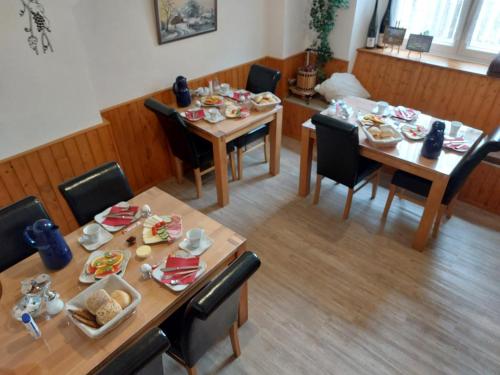 un comedor con 2 mesas y sillas con comida. en Gästehaus Kretschmann, en Zeltingen-Rachtig