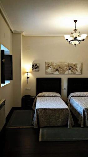 a bedroom with two beds and a chandelier at Hotel Rural Palacio de Galceran in Sotiello
