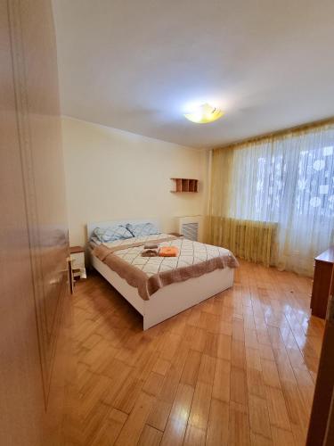 a bedroom with a bed and a wooden floor at Квартира in Astana