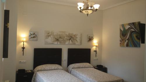 two beds in a bedroom with two pictures on the wall at Hotel Rural Palacio de Galceran in Sotiello