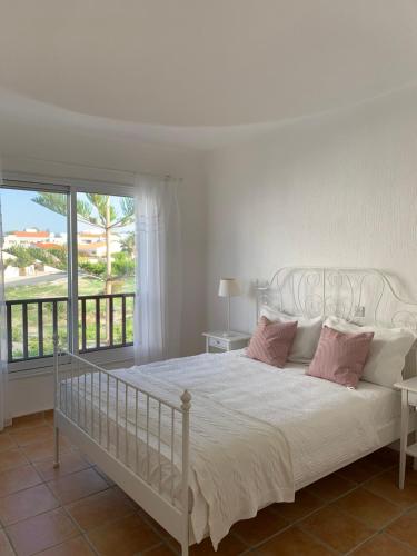 ein weißes Bett mit rosa Kissen im Schlafzimmer in der Unterkunft Villa Celine in Klorakas