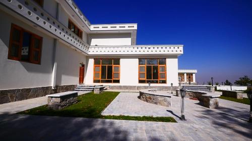 una casa blanca con dos bancos delante en Istalif Palace Hotel 