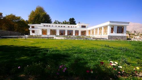 a large white building with a grass field in front of it at Istalif Palace Hotel 