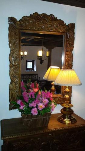 a table with a lamp and flowers in front of a mirror at Hotel Rural Palacio de Galceran in Sotiello