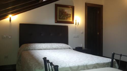 a bedroom with a bed with a black headboard at Hotel Rural Palacio de Galceran in Sotiello
