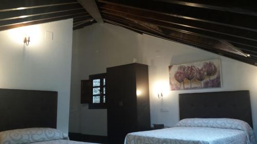 a bedroom with two beds and a painting on the wall at Hotel Rural Palacio de Galceran in Sotiello