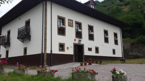 a white building with flowers in front of it at Hotel Rural Palacio de Galceran in Sotiello