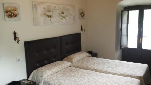 a bedroom with a bed with a black headboard at Hotel Rural Palacio de Galceran in Sotiello