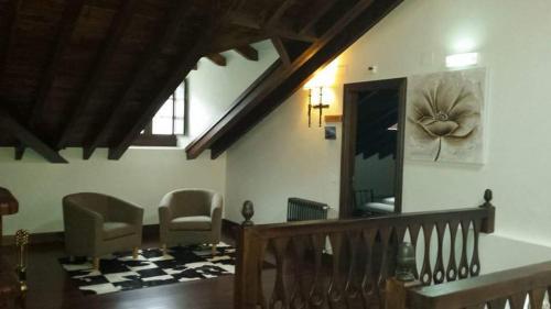 a living room with chairs and a staircase with a painting on the wall at Hotel Rural Palacio de Galceran in Sotiello