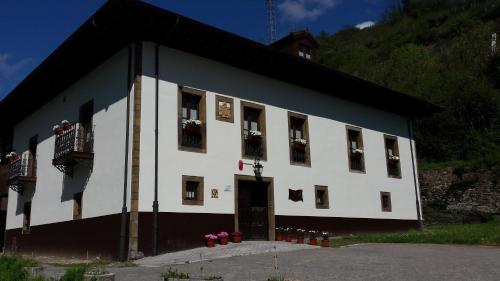 a white building with flowers in the windows at Hotel Rural Palacio de Galceran in Sotiello