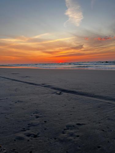 - un coucher de soleil sur la plage avec des empreintes sur le sable dans l'établissement Przy Kolonijnej, à Ostrowo