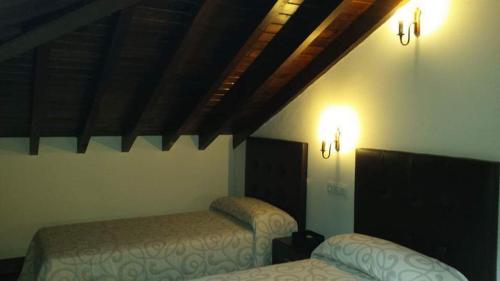 a bedroom with two beds and two lights on the wall at Hotel Rural Palacio de Galceran in Sotiello
