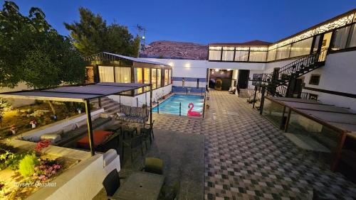 a house with a swimming pool and a woman in a pink swimsuit at Al Namteh Lodge in ‘Ābil