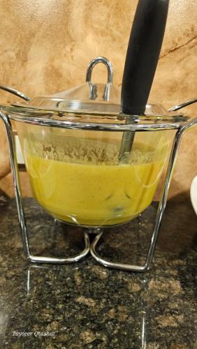 a bowl of yellow liquid with a knife in it at Al Namteh Lodge in ‘Ābil