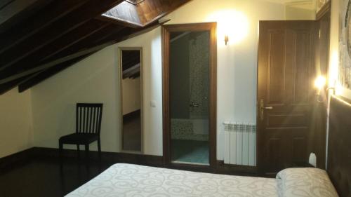 a bedroom with a bed and a chair and a door at Hotel Rural Palacio de Galceran in Sotiello