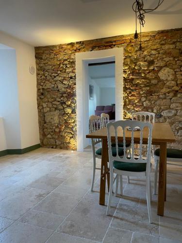 a dining room with a stone wall and a table and chairs at La Petite Fenêtre in Casale Marittimo