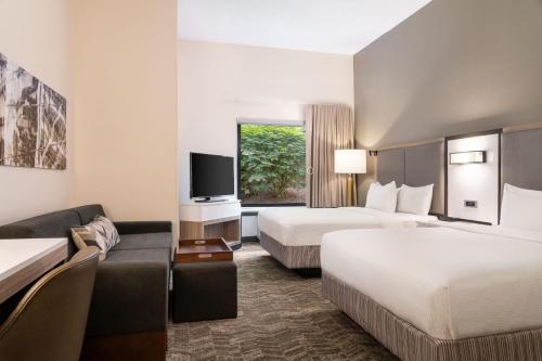ウェストミフリンにあるSpringHill Suites West Mifflinのベッド2台とソファが備わるホテルルームです。