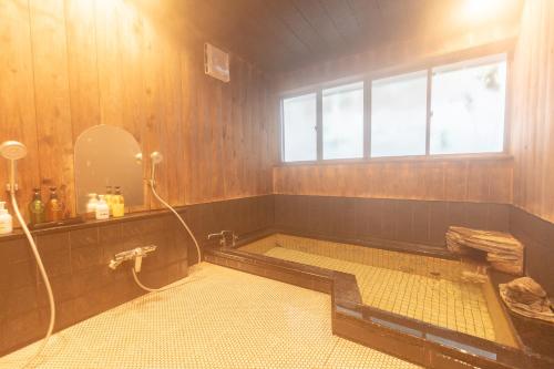 a bathroom with a bath tub with a window at Ryokan Hiyoshi in Chichibu
