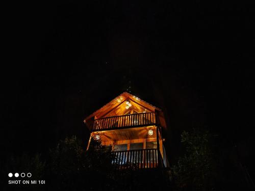 a wooden building with lights on it at night at The Tree Top Treehouse Jibhi in Jibhi