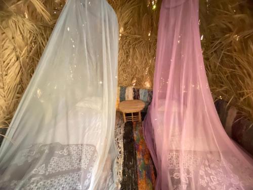 a room with curtains and a table and a wooden chair at Maya Corner in Siwa