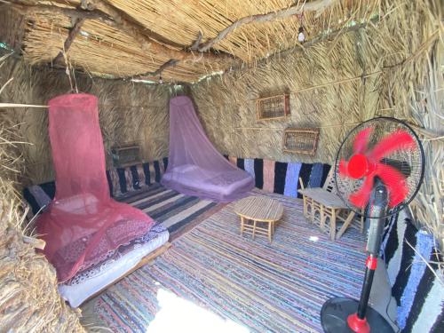 シワにあるMaya Cornerの藁小屋内のベッド2台と椅子が備わる客室です。