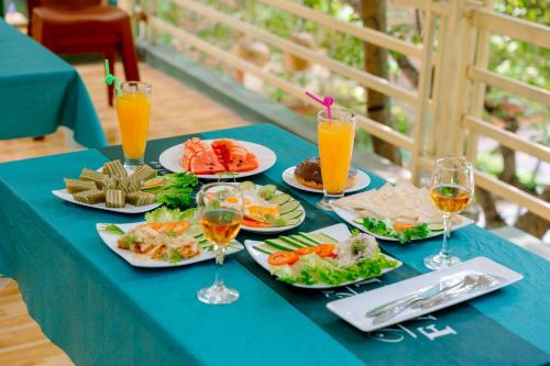 uma mesa azul com pratos de comida e copos de sumo de laranja em Mai Mountain Homestay em Ninh Binh