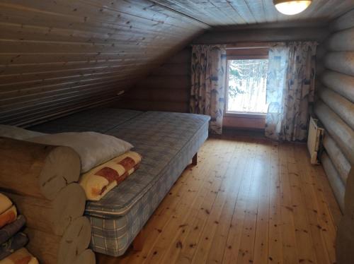 Blockhausschlafzimmer mit 2 Betten und einem Fenster in der Unterkunft Kalliorinteen Mökit Kalliopirtti in Töysä