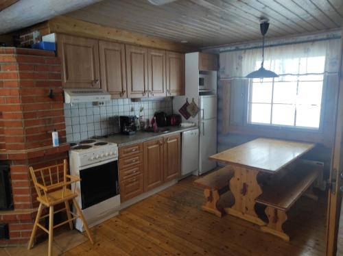 eine Küche mit Holzschränken, einem Tisch und einem Herd in der Unterkunft Kalliorinteen Mökit Kalliopirtti in Töysä