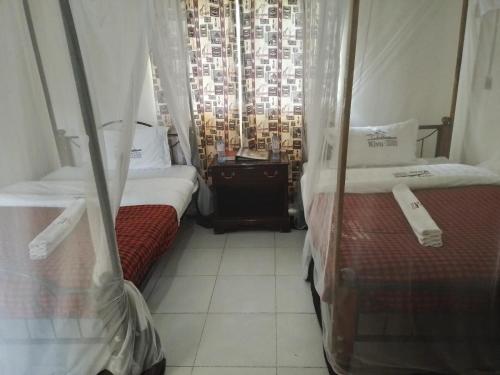 two beds in a room with a window at Kivu Resort in Nakuru