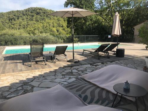 a pool with chairs and a table and an umbrella at Les Mazets de la Cascade in Salernes