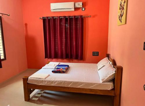 1 dormitorio con 1 cama con paredes de color naranja y ventana en Indira Homestay en Mangalore