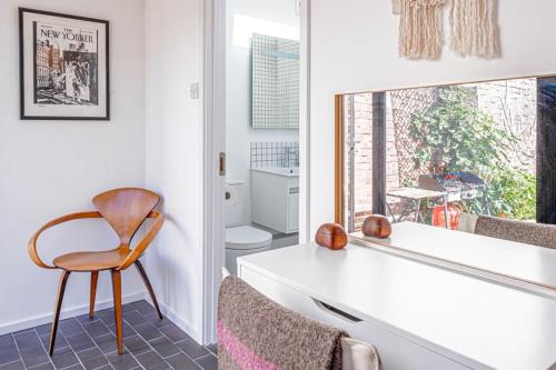 a bathroom with a white counter and a chair and a window at Gorgeous 1BD Balearic-style home with Gardens in Cheltenham