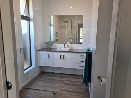 a bathroom with a sink and a mirror at Coastal Palms - relax by the golf course in Normanville