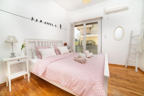 a white bedroom with a pink bed with birds on it at Cosy Apartment With Acropolis View in Athens