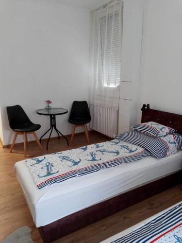 a bedroom with a bed with two chairs and a table at Átutazó Apartman in Nyíregyháza