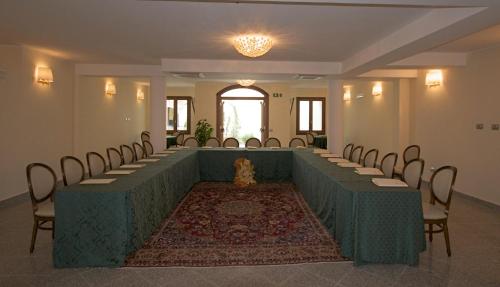 Habitación grande con una fila de mesas y sillas. en Hotel Hieracon en Carloforte
