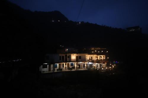a house at night with a mountain in the background at PerfectPlus Mussoorie in Mussoorie