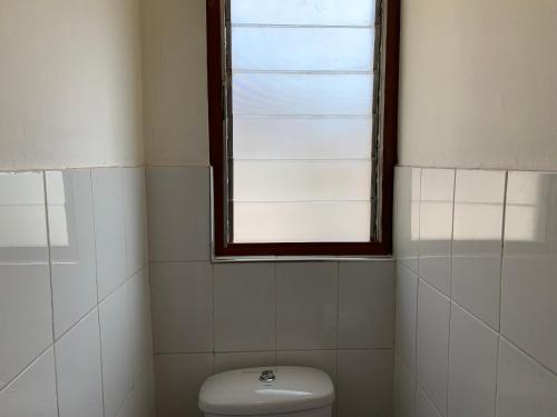 a bathroom with a toilet and a window at One Cozy Bedroom in a shared apartment in Kumasi